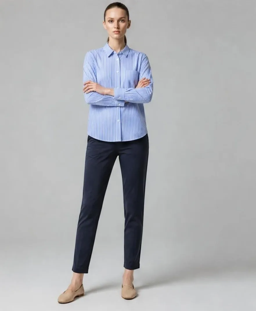 AI-generated studio photo of a model in a blue striped shirt and navy chinos, standing with arms crossed