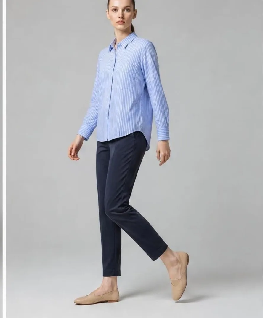AI-generated studio photo of a model walking in a blue striped shirt, navy chinos, and tan loafers