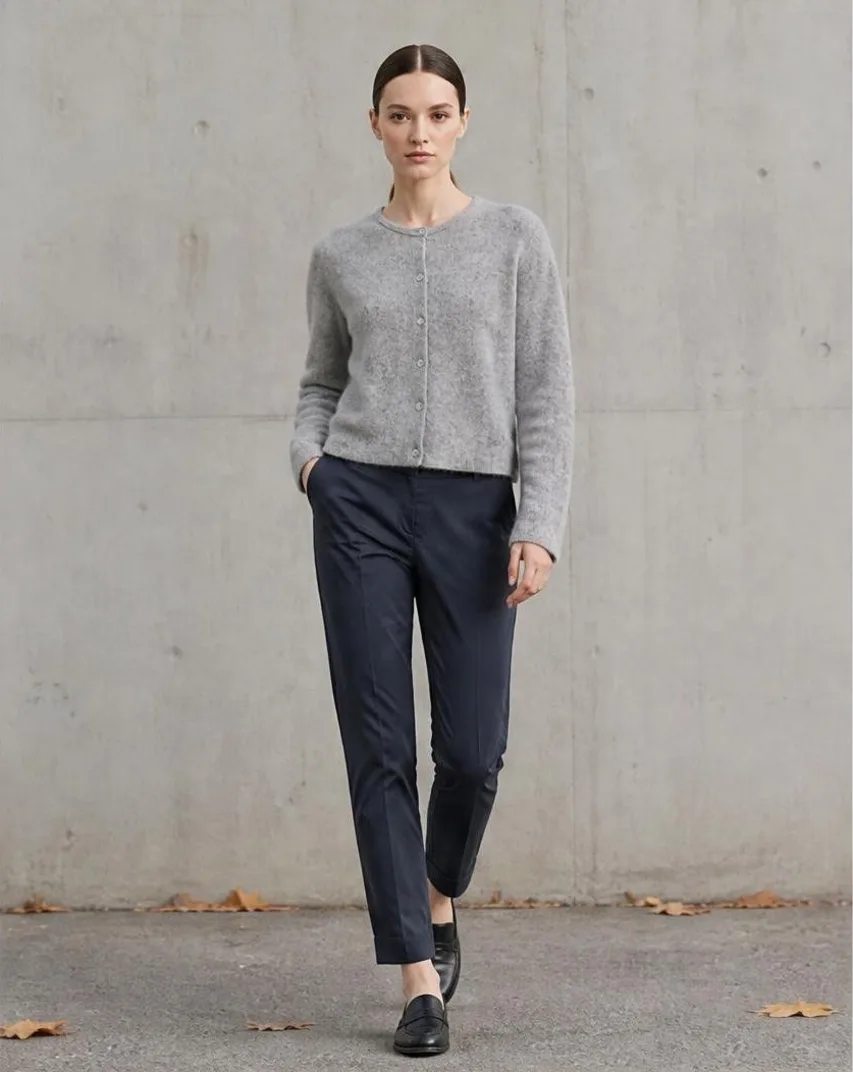 AI-generated outdoor photo of a model walking in a grey cardigan and navy trousers against a concrete wall