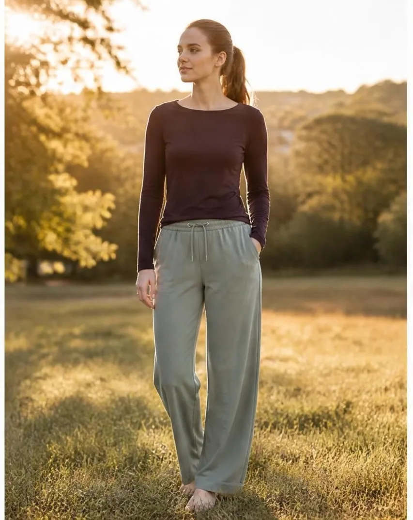 AI-generated outdoor photo of a model wearing a maroon top and sage lounge pants in a sunlit golden field