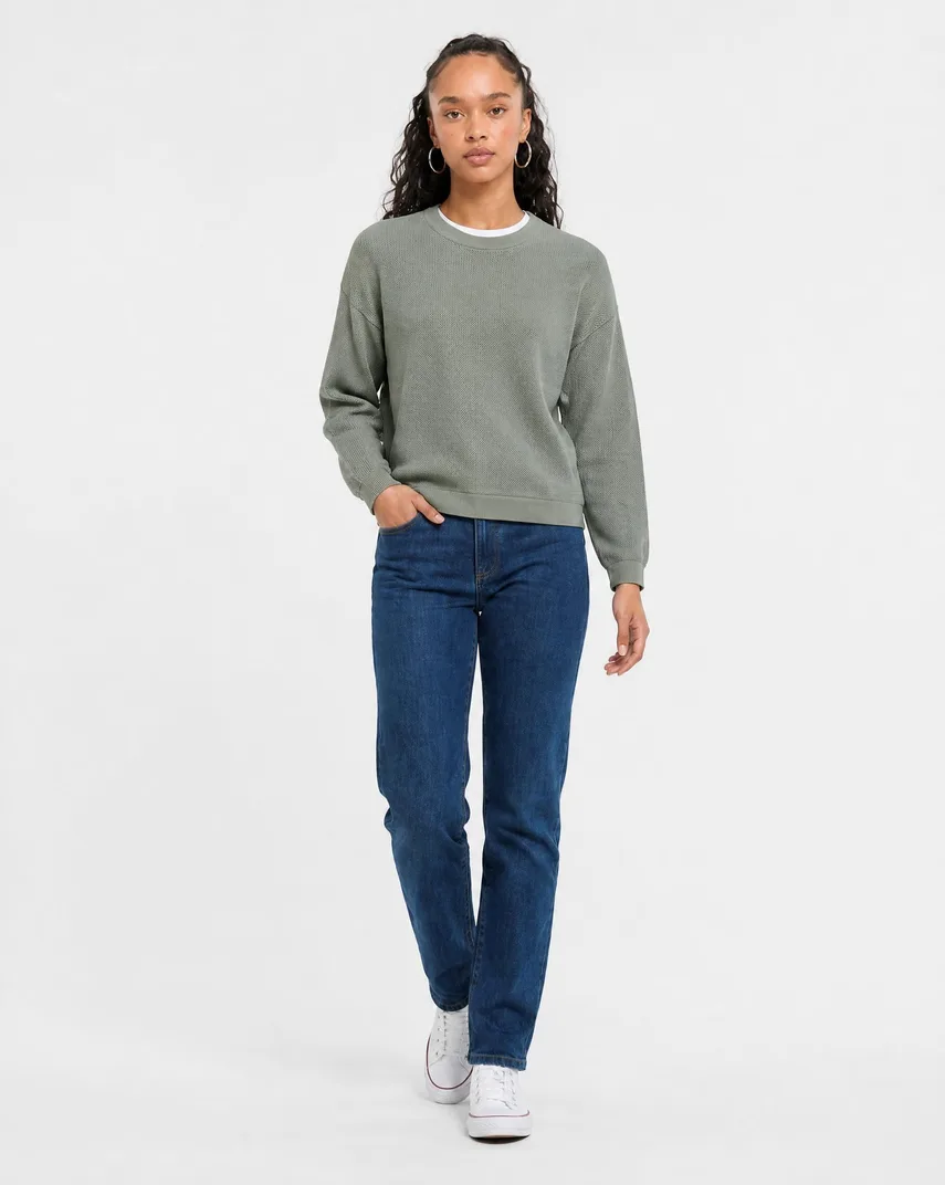 The same model mid-stride in the same straight-leg jeans, one hand in the front pocket, showing how the leg falls while walking